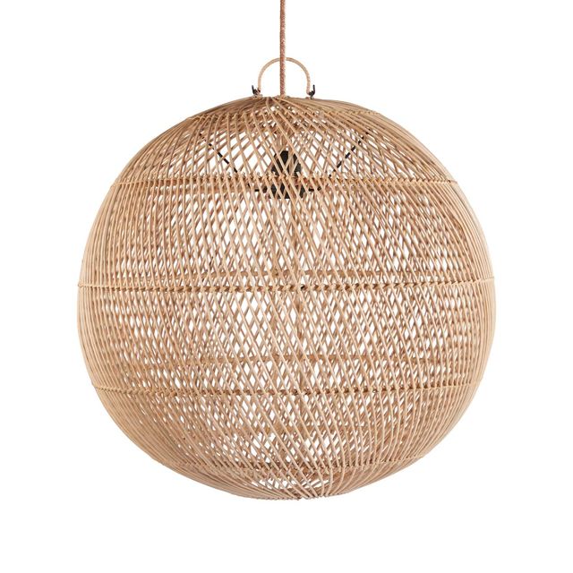 A large spherical woven rattan pendant light hangs in a warm, sunlit room with beige walls, a wooden chair, shelves, and a window.