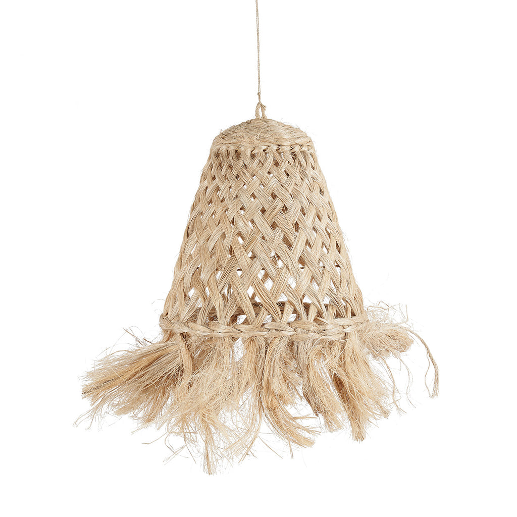 A bohemian-style woven rattan pendant light with a natural straw fringe, hanging in a warm, neutral-toned room above a rustic wooden stool and a cozy cushioned bench.
