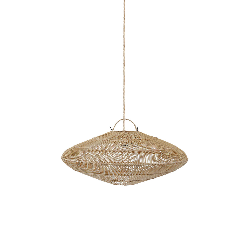 A large woven oval pendant light hangs over a cream sofa in a warm, neutral-toned living room with a rustic wooden coffee table, textured pillows, and potted plants.