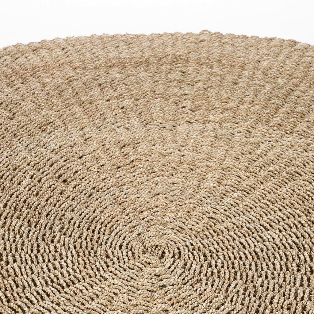 Round woven round fibre rug on a white background